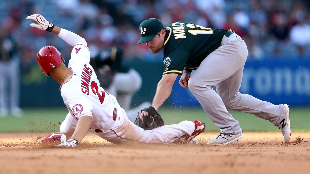Angels shortstop Andrelton Simmons is tagged out by Athletics second baseman Max Muncy while trying to stretch a single into a double during the fifth inning.
