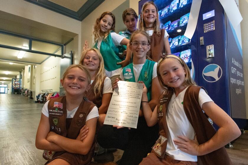 Members of Girl Scout Troop 2383 sit in front of a book vending machine they donated to Newport Elementary School.