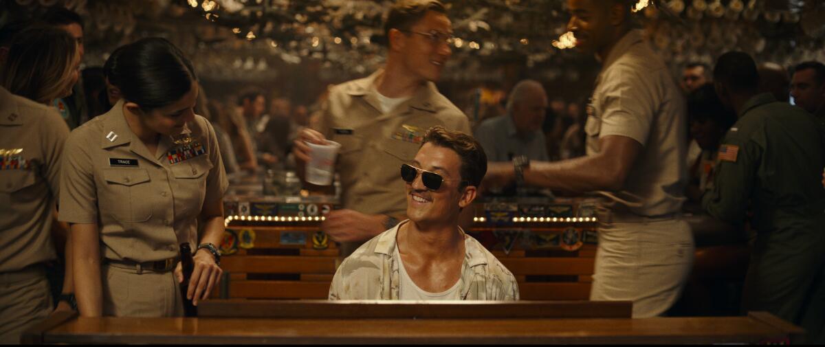 Miles Teller (center) plays piano in "Top Gun: Maverick." Also pictured: Monica Barbaro, Lewis Pullman and Jay Ellis.