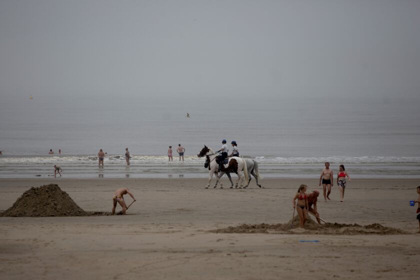 Police patrol the beach on horseback at the Belgian seaside resort of Blankenberge, Belgium, Tuesday, Aug. 11, 2020. A skirmish took place on the beach on Saturday, Aug. 8, 2020 which resulted in two coastal communities banning day trippers from the city. (AP Photo/Virginia Mayo)