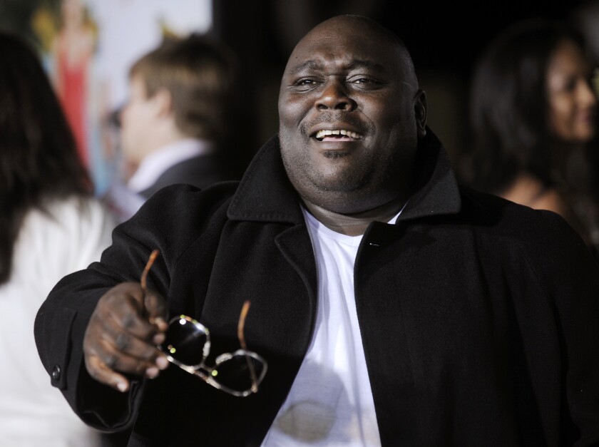 Faizon Love holding a pair of sunglasses.
