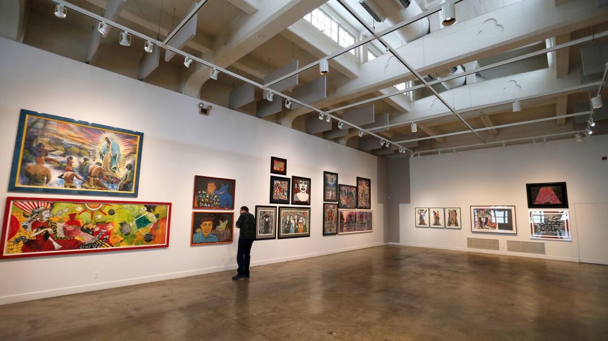 A visitor to the Riverside Art Museum looks at works from the collection of actor Cheech Marin, known for his collection of Chicano art.