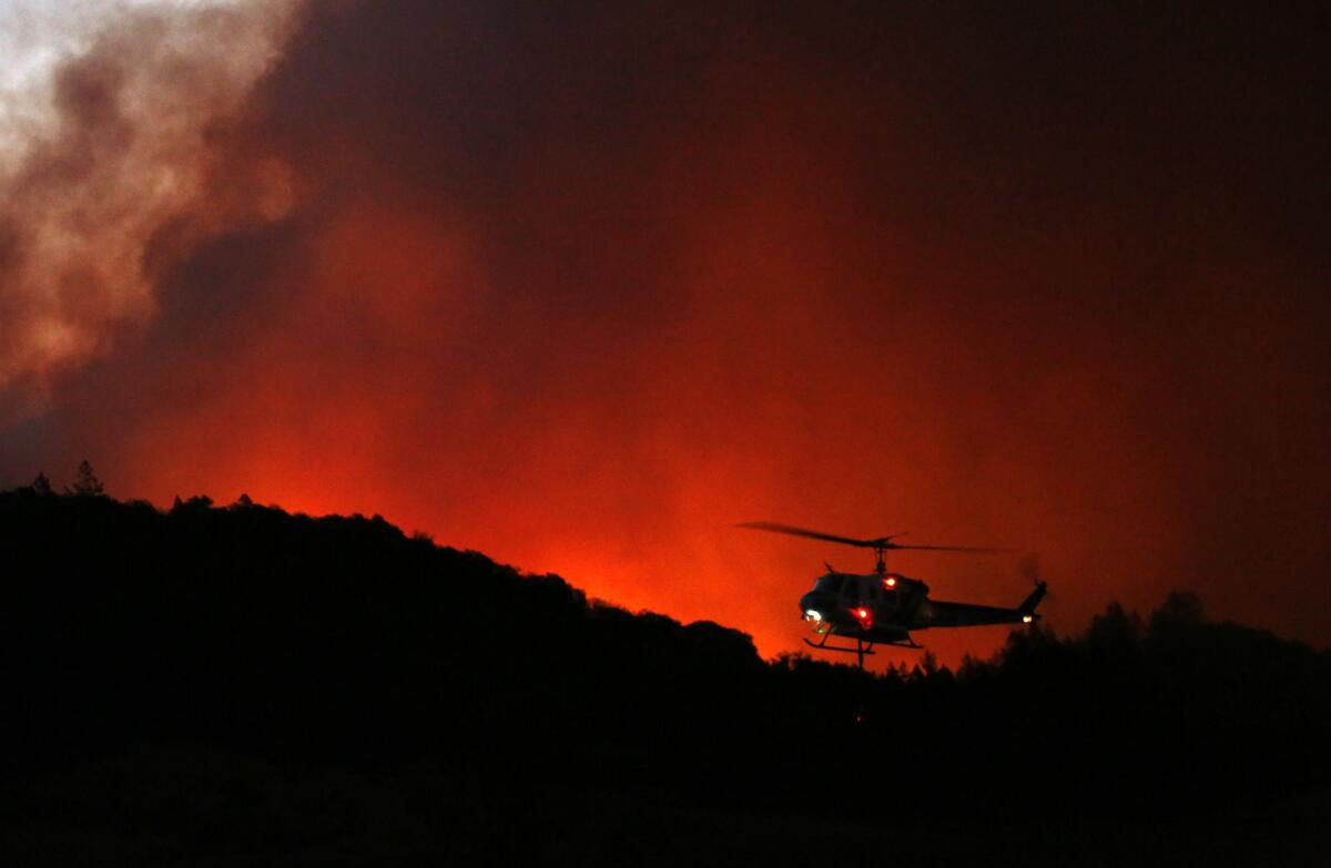 A helicopter prepares to drop water on a fire threatening the Oakmont community along Highway 12 in Santa Rosa on Oct. 13.