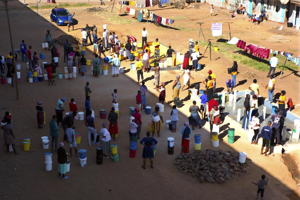 In this April 24 photo, people wait to fetch water from a row of communal taps that the group Doctors Without Borders provided in a suburb of Harare, Zimbabwe. In Zimbabwe, clean water is often saved for daily tasks like doing dishes and flushing toilets.