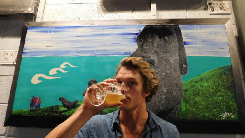 Richard James Yozamp enjoys a beer at Culture Brewing in front of one of his works. (Courtesy photo)