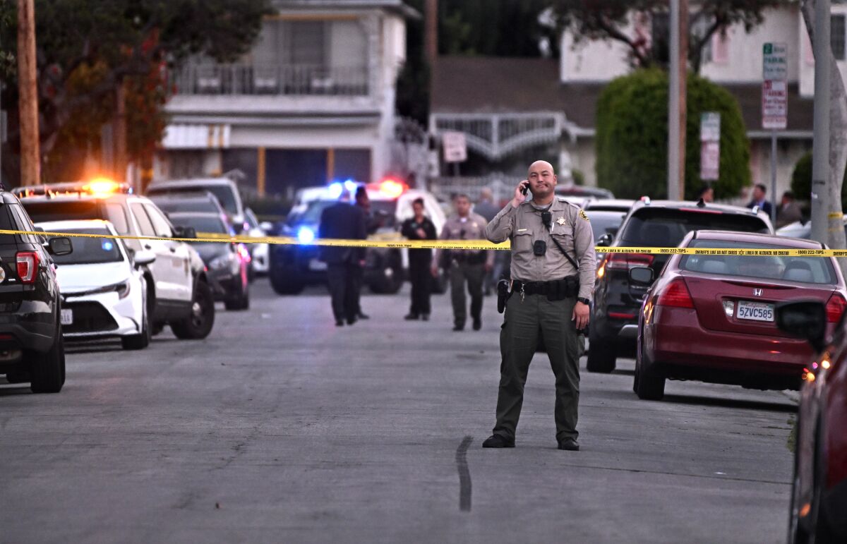 Law enforcement investigators comb the scene of a shooting along Blakley Ave. in Willowbrook