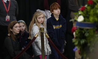 A woman and her three children behind a velvet rope