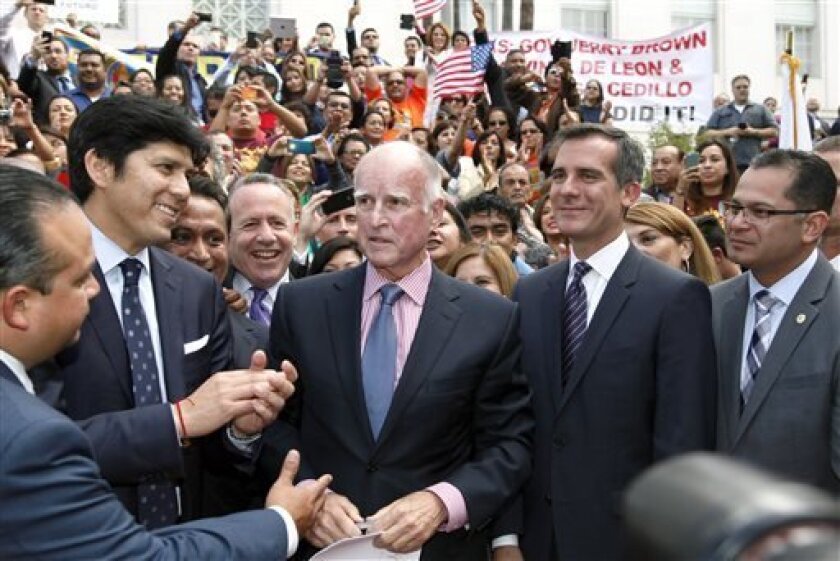 From left to right, Assemblyman Luis Alejo, D-Salinas, state Sen. Kevin DeLeon, D-Los Angeles, Los Angeles City Councilman, Gov. Jerry Brown, Los Angeles Mayor Eric Garcetti, and Assemblyman V. Manuel Perez, D-Coachella, celebrate after Brown signed a bill allowing illegal immigrants to obtain California drivers licenses at Los Angeles City Hall in Los Angeles Thursday, Oct 3, 2013. The bill adds California to the growing list of states allowing immigrants in the country illegally to obtain driv