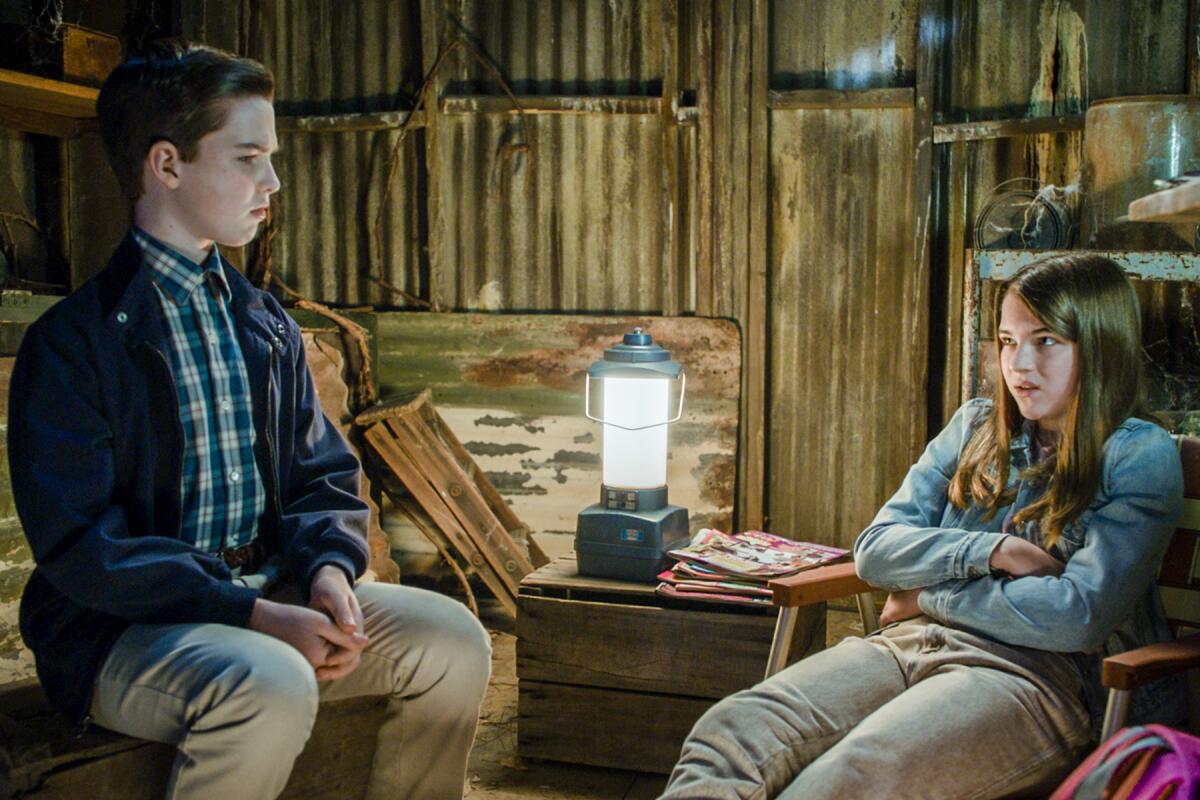 Iain Armitage and Raegan Revord sitting in a rustic shack on "Young Sheldon" on CBS.