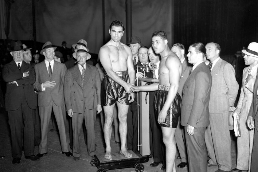 June 18, 1936 -- Heavyweight boxers Max Schmeling, standing on scale, and Joe Louis shake hands at the weigh-in ceremony for their 15-round bout at Yankee Stadium.