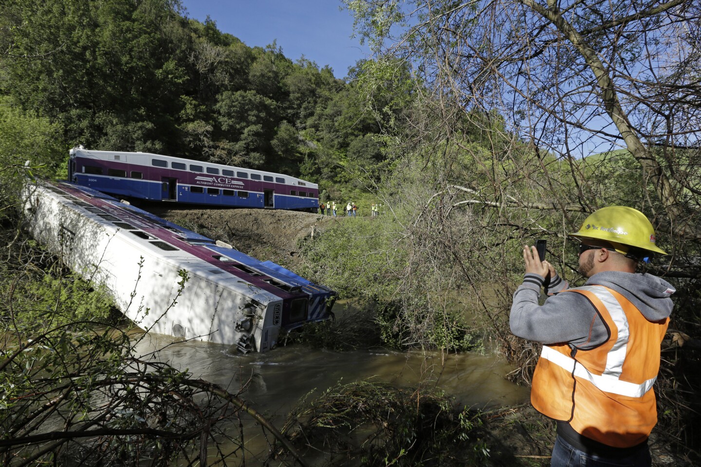 Workers investigate the scene of a derailed Altamont Corridor Express train Tuesday in Sunol, Calif. A Union Pacific spokesman says a mudslide most likely caused a commuter train derailment in Northern California that sent its leading car plunging into a swollen creek, injuring several people.