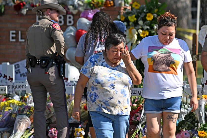 Uvalde, Texas May 26, 2022- Family members walk away after living flowers at a memorial outside Rob Elementary School in Uvalde, Texas. Nineteen students and two teachers died when a gunman opened fire in a classroom Tuesday. (Wally Skalij/Los Angeles Times)