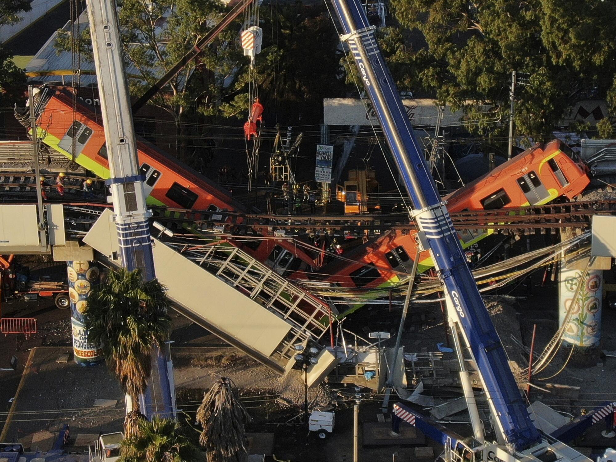 An aerial view of subway cars dangling at an angle from a collapsed elevated section of the Metro line.