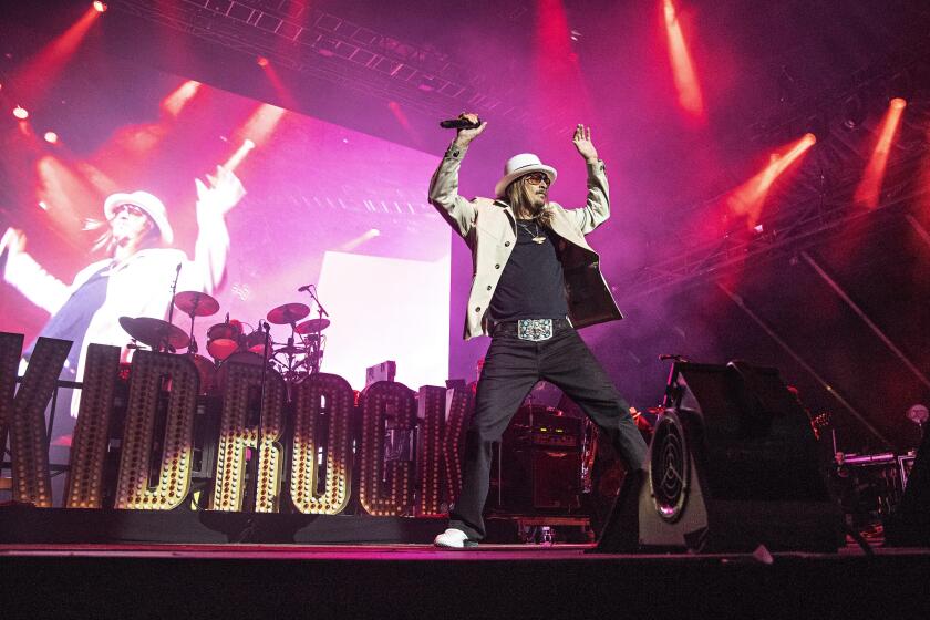 A man with a hat performs in pink lighting