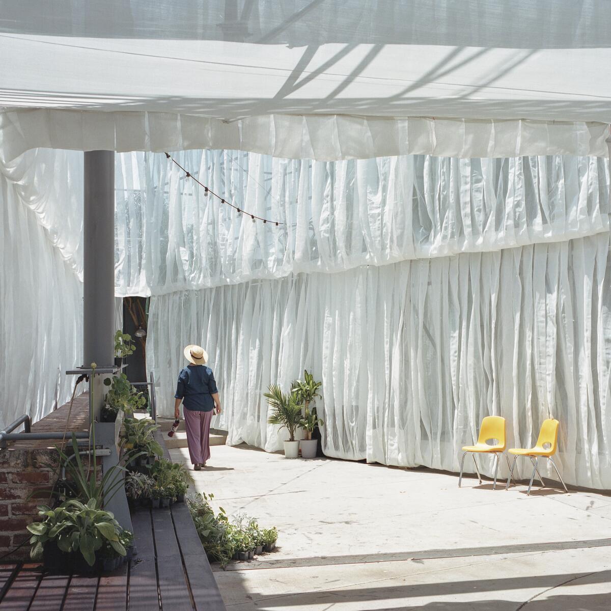 A person walks through a triangular courtyard whose multiple levels are wrapped in white fabric