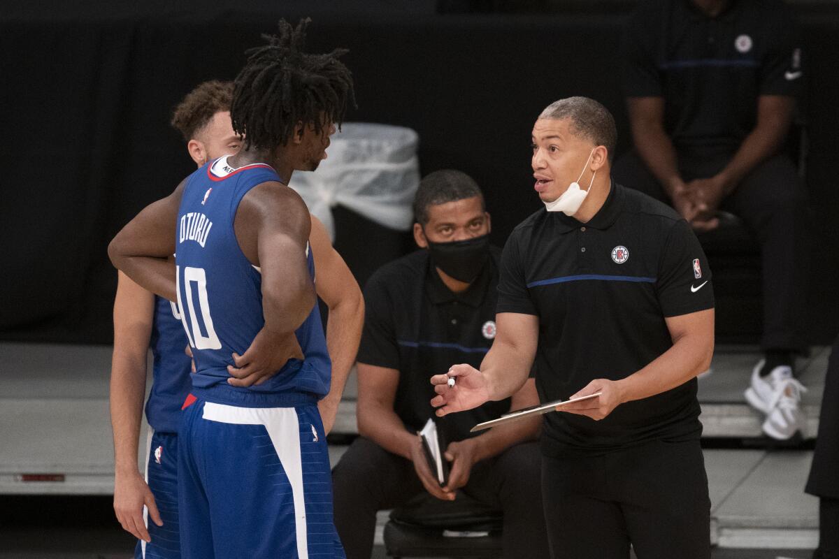 Clippers coach Tyronn Lue, right, gives instructions to forward Daniel Oturu and guard Jordan Ford.