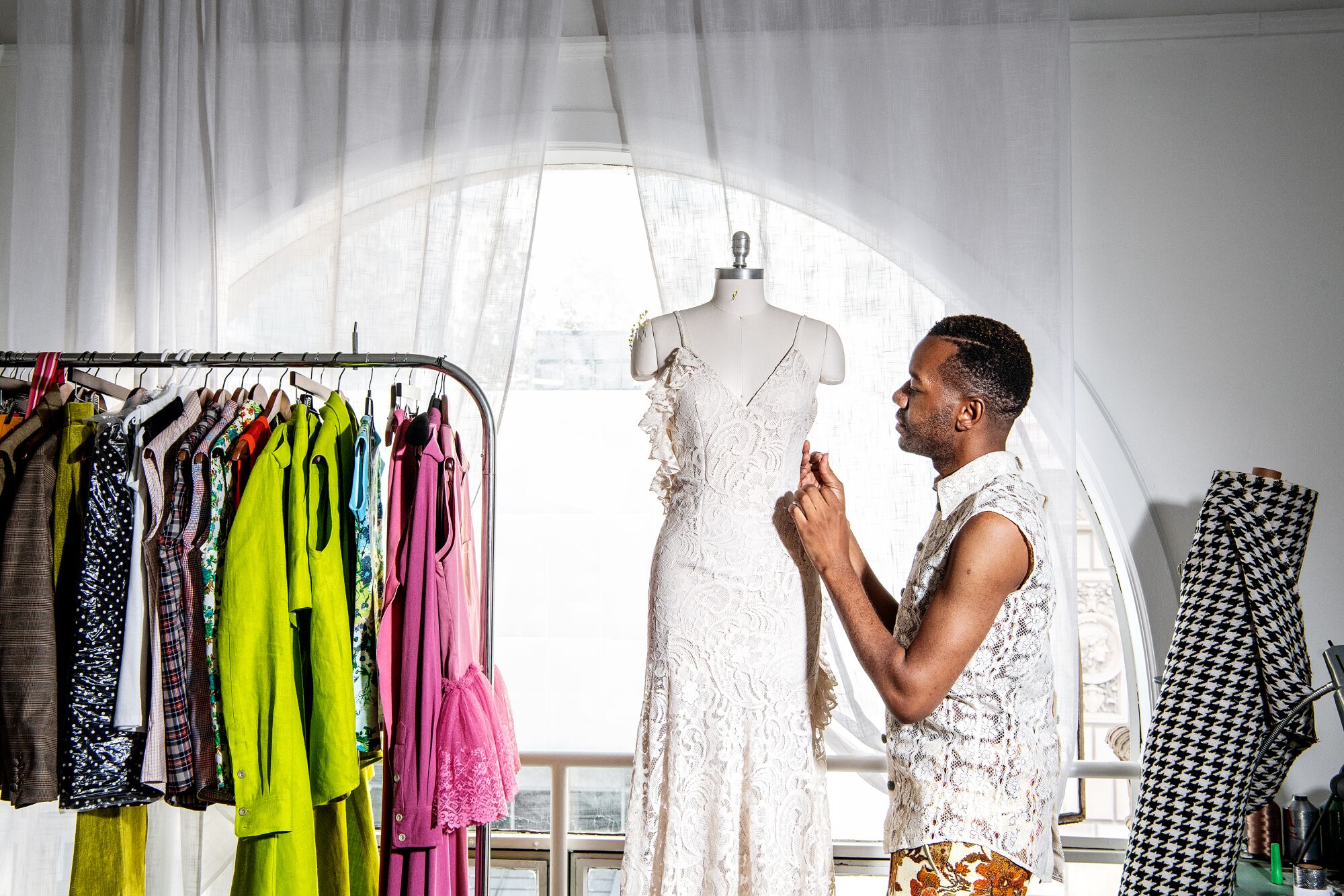 Portrait of fashion designer Kenneth Nicholson wearing a sleeveless lace tailored shirt with contrasting velvet buttons.
