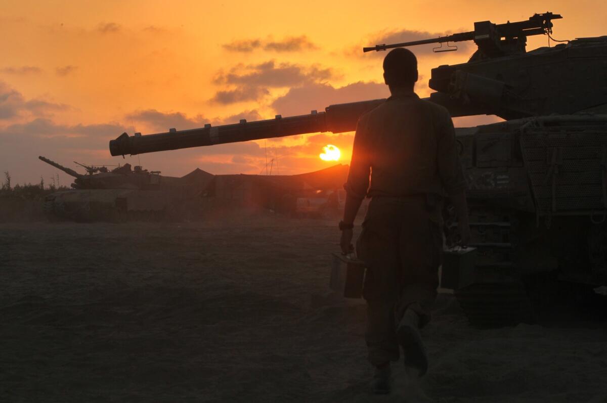 An Israeli soldier walks past a Merkava tank along the border between Israel and the Hamas-controlled Gaza Strip after returning from combat in the Palestinian enclave.