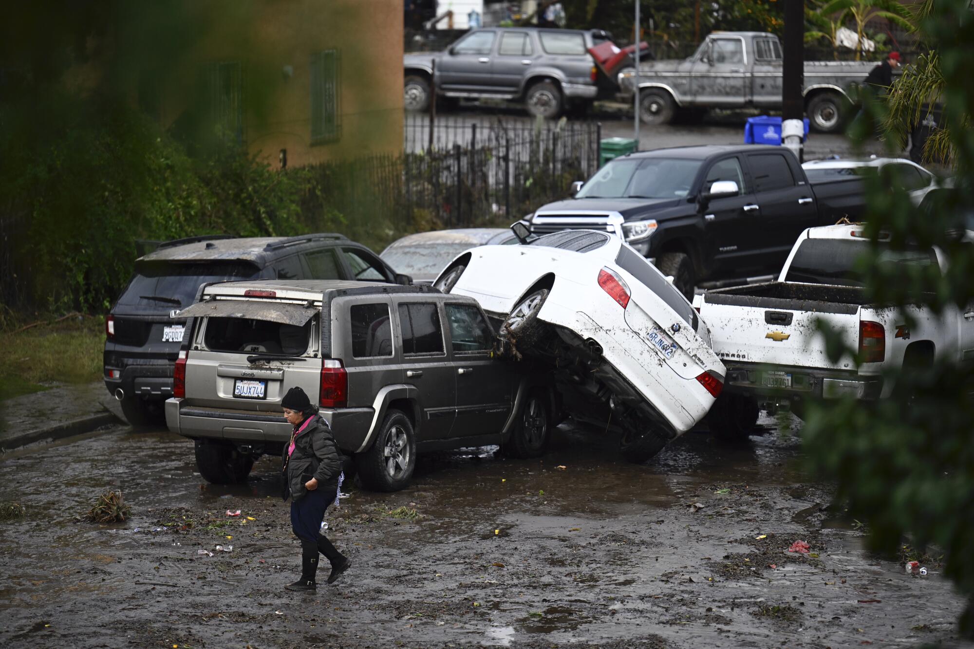 A woman walks by cars damaged by floods during a rainstorm in San Diego.