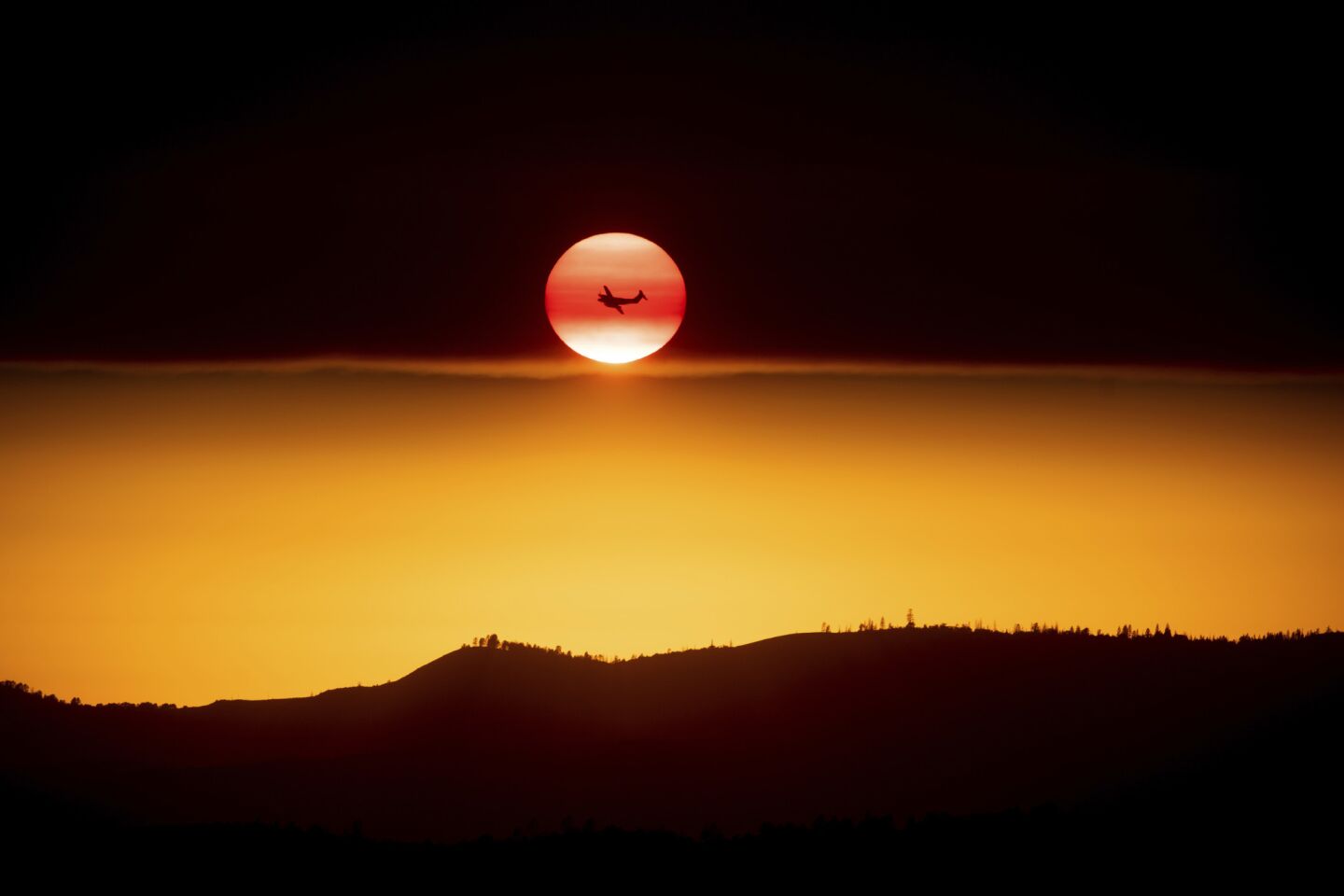 A plane battling the Ferguson fire is silhouetted against the setting sun in unincorporated Mariposa County, near Yosemite National Park.