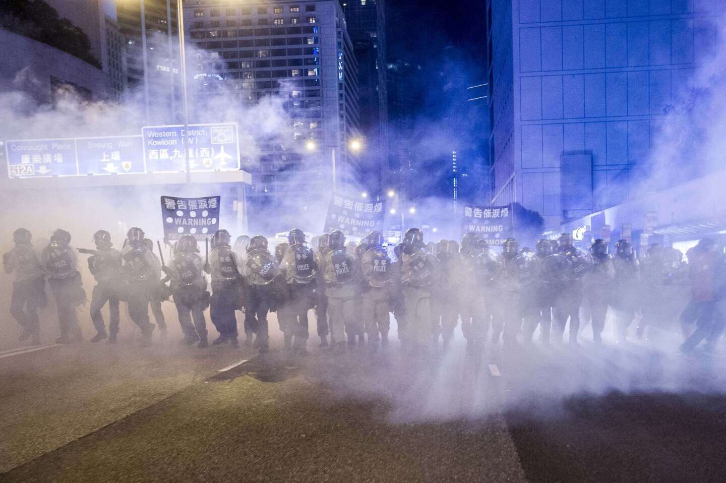 Police officers stand in a cloud of tear gas during a demonstration in Hong Kong.