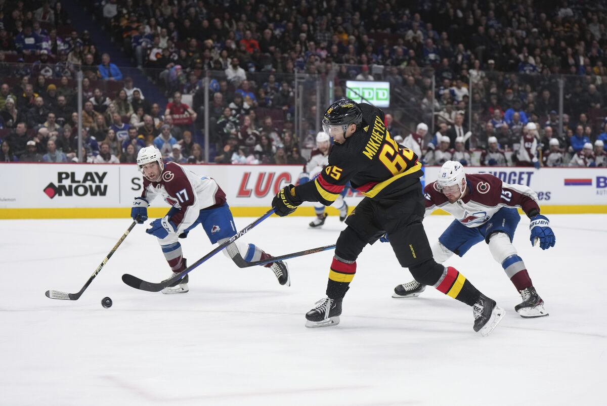 Vancouver Canucks' Ilya Mikheyev shoots as Colorado Avalanche's Brad Hunt (17) and Valeri Nichushkin (13) defend during the first period of an NHL hockey game Friday, Jan. 20, 2023, in Vancouver, British Columbia. (Darryl Dyck/The Canadian Press via AP)