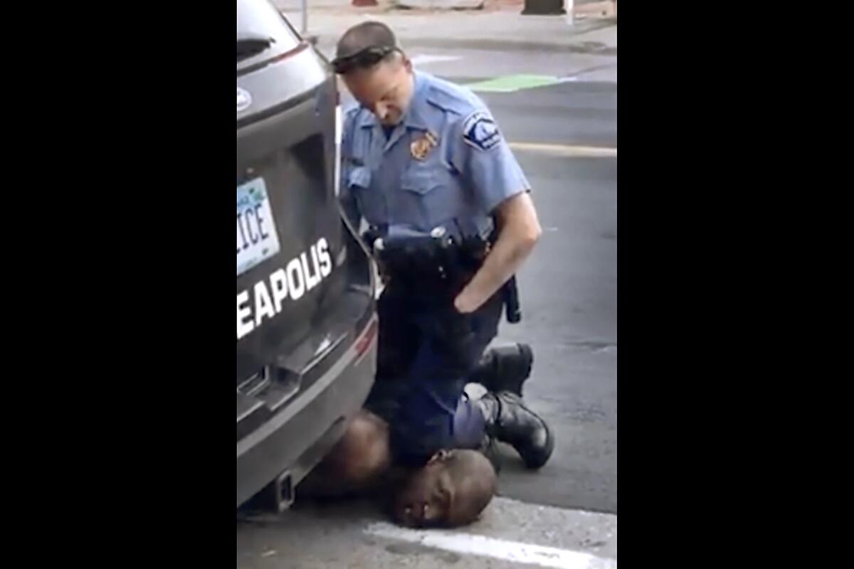 A Minneapolis officer kneels on the neck of a handcuffed man.