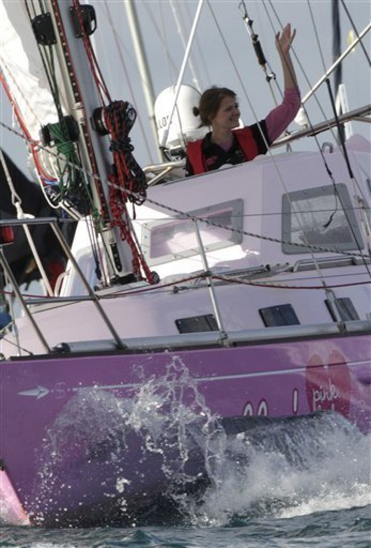 Sixteen-year-old Jessica Watson waves as she sails past the finish line at the entrance to Sydney Harbour in Sydney, Australia, Saturday, May 15, 2010, capping off a nearly 23,000 nautical miles voyage. Watson crossed the finish line of her round-the-world journey Saturday, becoming the youngest person to sail solo, nonstop and unassisted around the world. (AP Photo/Rob Griffith)
