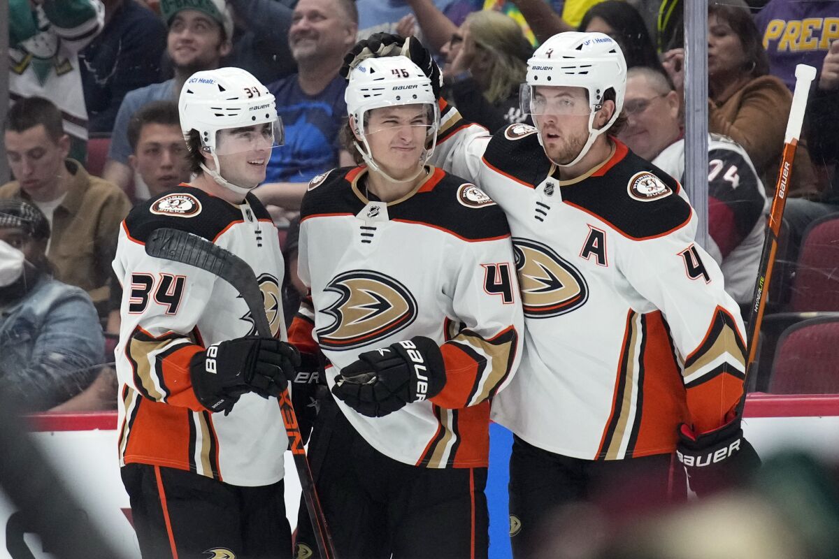 Anaheim Ducks center Trevor Zegras (46) celebrates with defensemen Jamie Drysdale (34) and Cam Fowler (4) after scoring a goal against the Arizona Coyotes during the first period of an NHL hockey game Friday, April 1, 2022, in Glendale, Ariz. (AP Photo/Rick Scuteri)