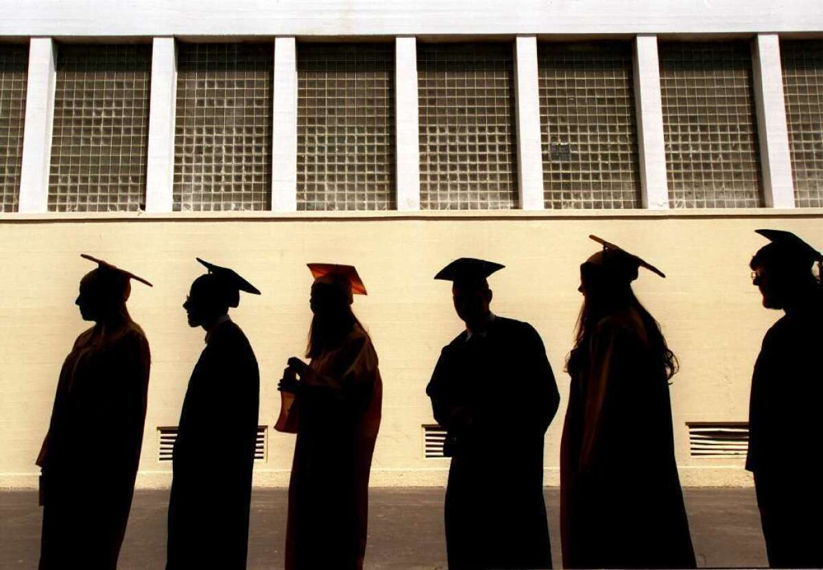 Students in caps and gowns line up at a high school graduation.