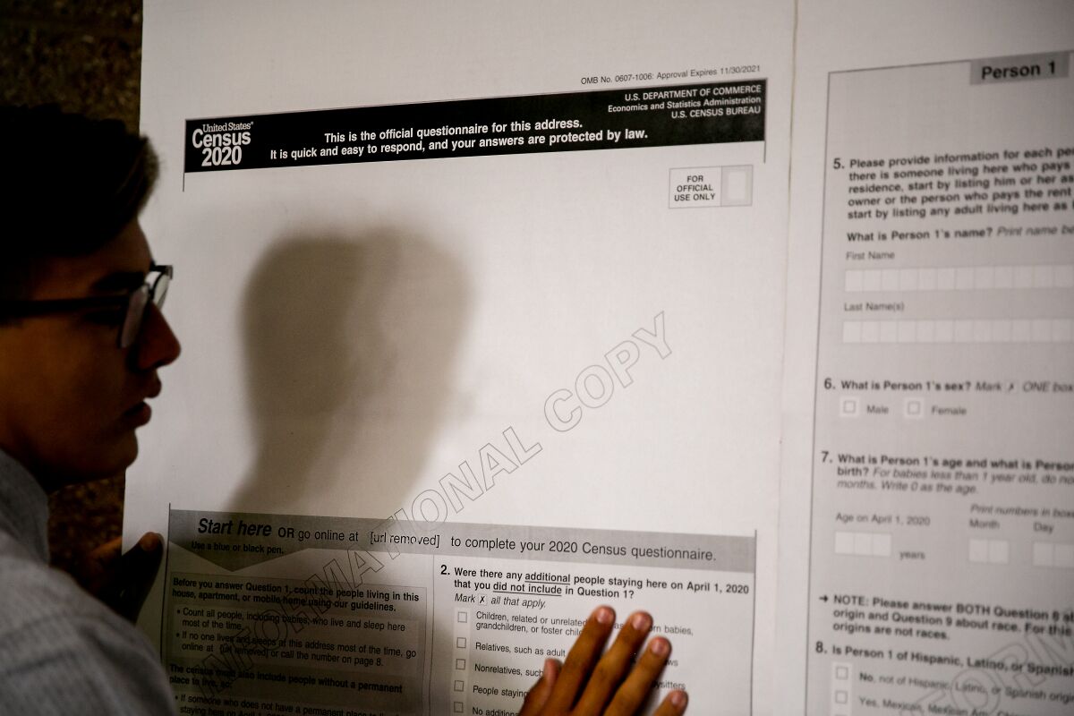 Matthew Carrillo, 16, hangs up a sample copy of the 2020 Census