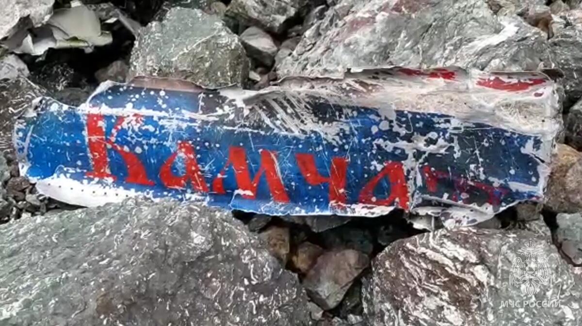This photo taken from video released by the Russia Emergency Situations Ministry press service on Wednesday, July 7, 2021, shows a part of the wreckage of a missing Antonov An-26 missing plane found near its destination airport outside the town of Palana, in Russia's Far East. Authorities in Russia say rescuers have found the bodies of nine victims a day after a plane crash in a remote area in the country's Far East. The world reads Kamchatka. (Russia Emergency Situations Ministry press service via AP)