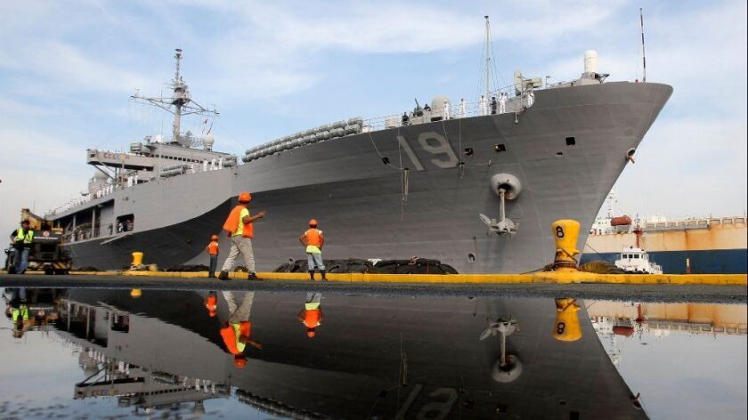 In this 2010 file photo, port workers prepare the docking of the USS Blue Ridge, the flagship of the US Navy Seventh Fleet, at Manila South Harbor in the Philippines. An email about the ship is part of a Navy bribery scandal being prosecuted in federal court in San Diego.