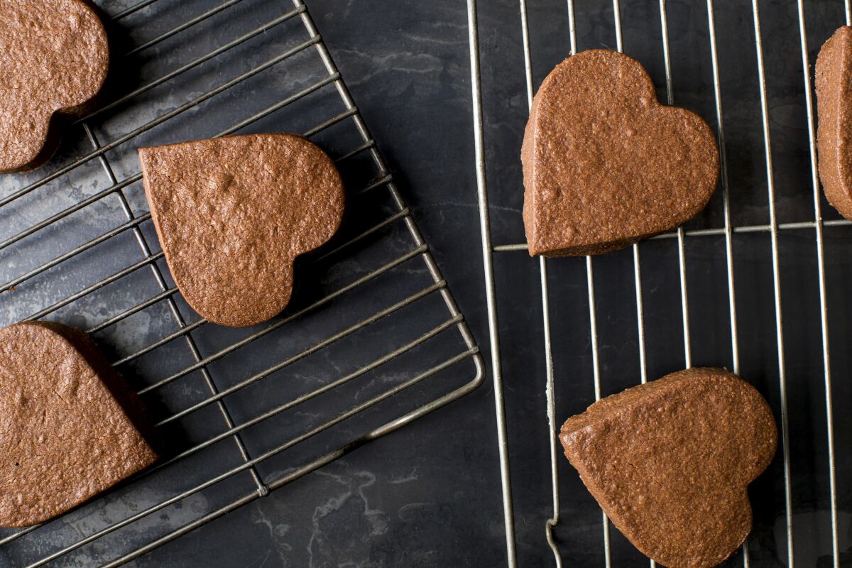 Heart-shaped chocolate shortbread cookies cool on a rack.
