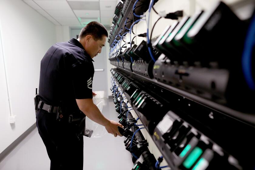 Gary CoronadoLos Angeles Times LAPD Sgt. Steve Wang loads body cameras at the Metropolitan Division. “It helps both sides of the camera,” Chief Michel Moore said of the devices’ impact.