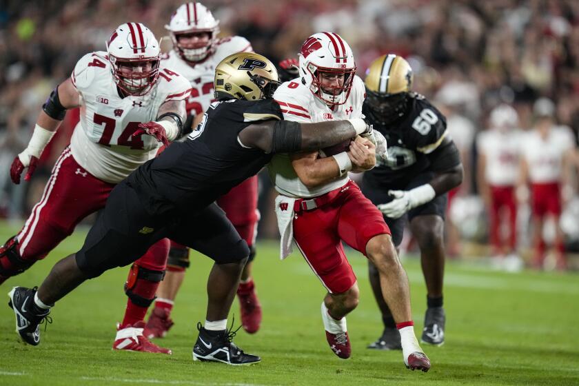 Wisconsin quarterback Tanner Mordecai (8) is tackled by Purdue linebacker Nic Scourton (5) during the first half of an NCAA college football game in West Lafayette, Ind., Friday, Sept. 22, 2023. (AP Photo/Michael Conroy)
