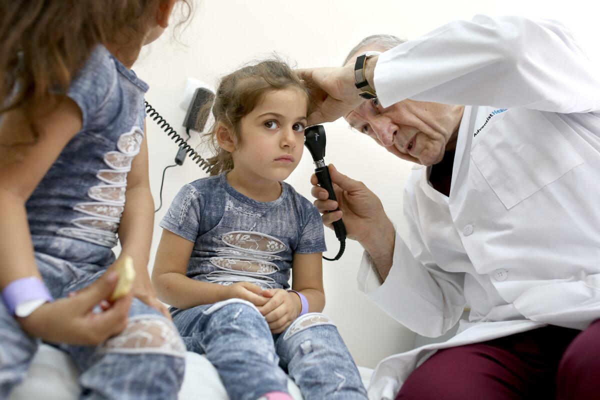 A pediatrician examines a child's ear.