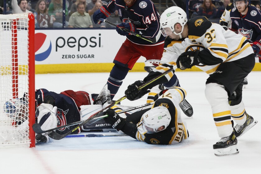 Boston Bruins' Patrice Bergeron, right, scores against Columbus Blue Jackets' Elvis Merzlikins, left, as Taylor Hall fights for the rebound during the third period of an NHL hockey game Saturday, March 5, 2022, in Columbus, Ohio. (AP Photo/Jay LaPrete)