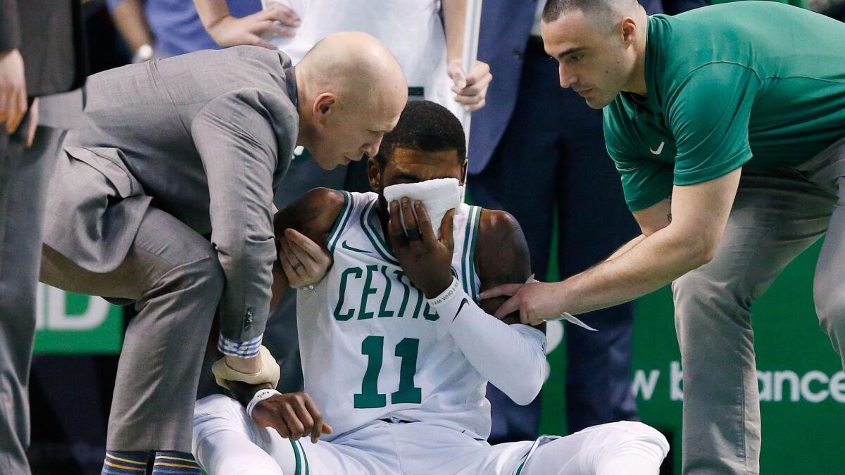 Team personnel assist Boston Celtics' Kyrie Irving after he was injured during the first quarter against the Charlotte Hornets in Boston on Friday. Irving took an elbow to the face and left the game.