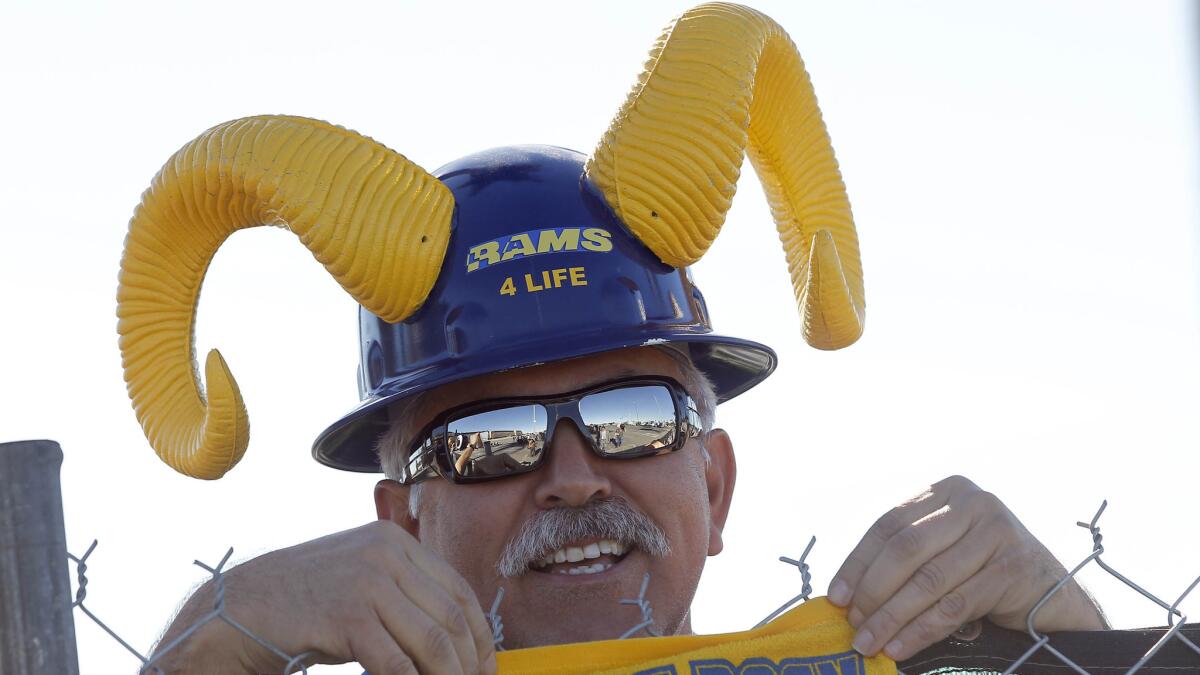 Rams fan Joe Ramirez stands behind a fence as officials with the Hollywood Park Land Co. unveiled a proposal for a new NFL stadium at Hollywood Park in Inglewood on Monday.