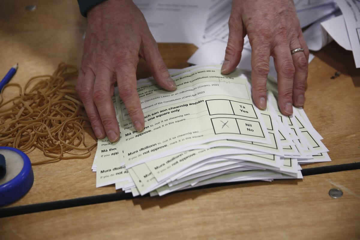 Two hands touch a stack of ballots.
