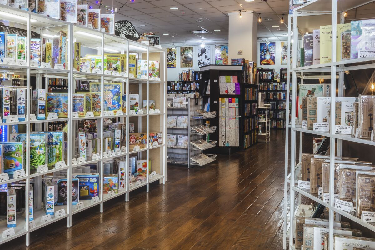 Rows of shelves featuring various games at Meeples Family.