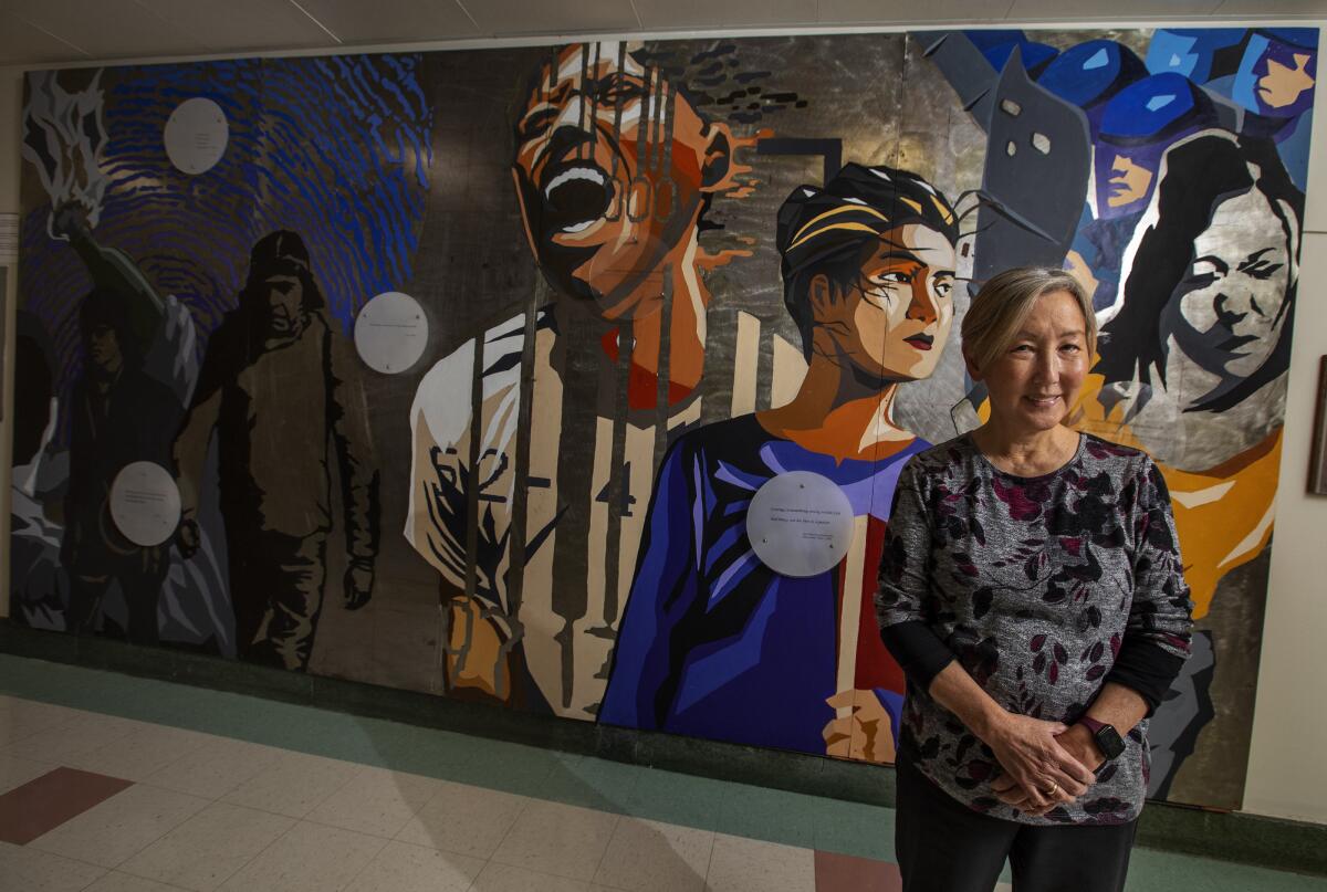 Karen Umemoto, director of the Asian American Studies Center at UCLA, stands next to a multicultural mural.