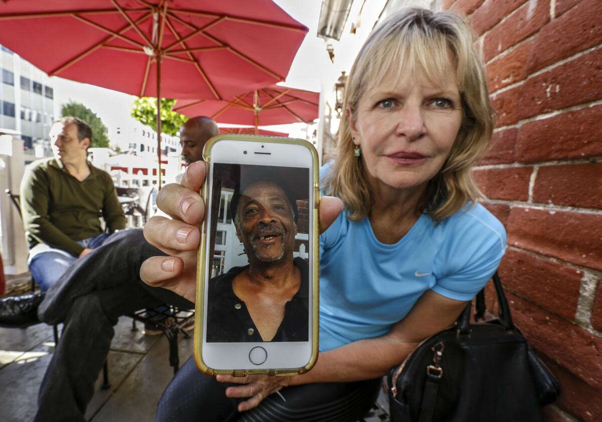 Maria Belknap shows a photo of George Saville on her phone. Belknap is part of a group of Beverly Hills cafe-goers who have embraced Saville, who is homeless and has run afoul of city officials.