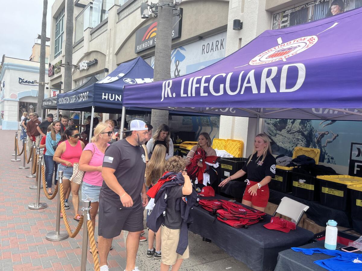 Huntington Beach Junior Lifeguards and their families choose equipment outside of Huntington Surf & Sport on Thursday.