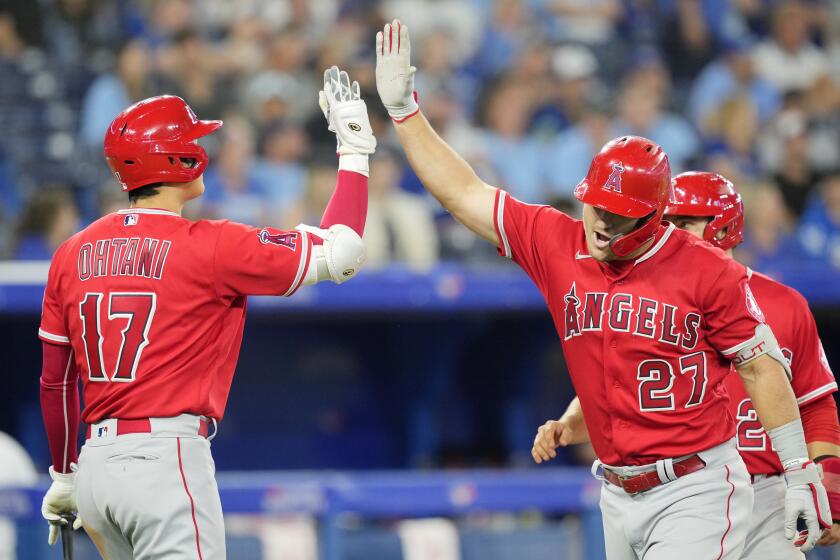 The Angels' Mike Trout (27) high-fives Shohei Ohtani after Trout homered in the eighth inning Aug. 26, 2022.