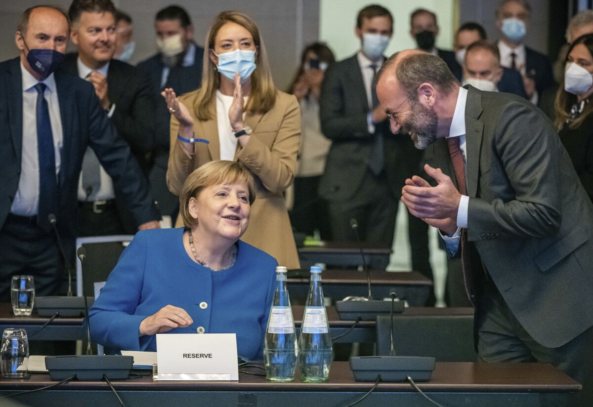 German Chancellor Angela Merkel, front left, accepts the applause next to Manfred Weber, front right, Chairman of the EPP Group, at the beginning of the closed session of the EPP Group Bureau of the European Parliament in Berlin, Germany, Thursday, Sept. 9, 2021. (Michael Kappeler/dpa via AP)