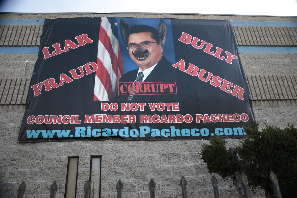 A banner with an image of a councilman with donkey ears and a nose, with the words liar, fraud, bully, abuser, corrupt