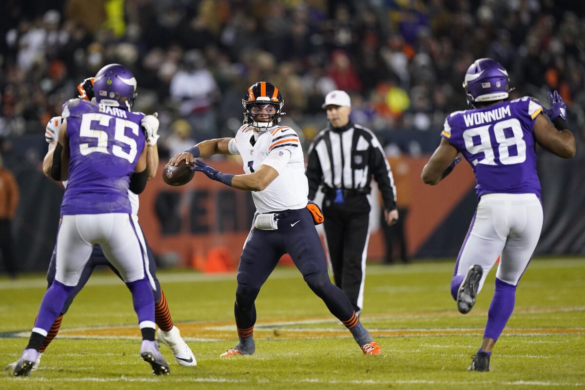 Chicago Bears quarterback Justin Fields (1) passes between Minnesota Vikings outside linebacker Anthony Barr (55) and defensive end D.J. Wonnum during the first half of an NFL football game Monday, Dec. 20, 2021, in Chicago. (AP Photo/Nam Y. Huh)