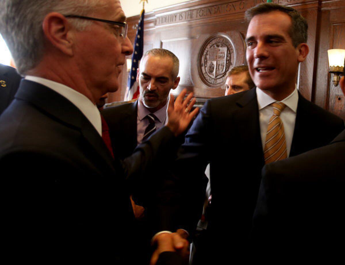 Los Angeles Mayor Eric Garcetti, right, shakes hands with Councilman Paul Krekorian after announcing that an agreement has been reached in contract negotiations with workers at the Department of Water and Power during a press conference at City Hall.